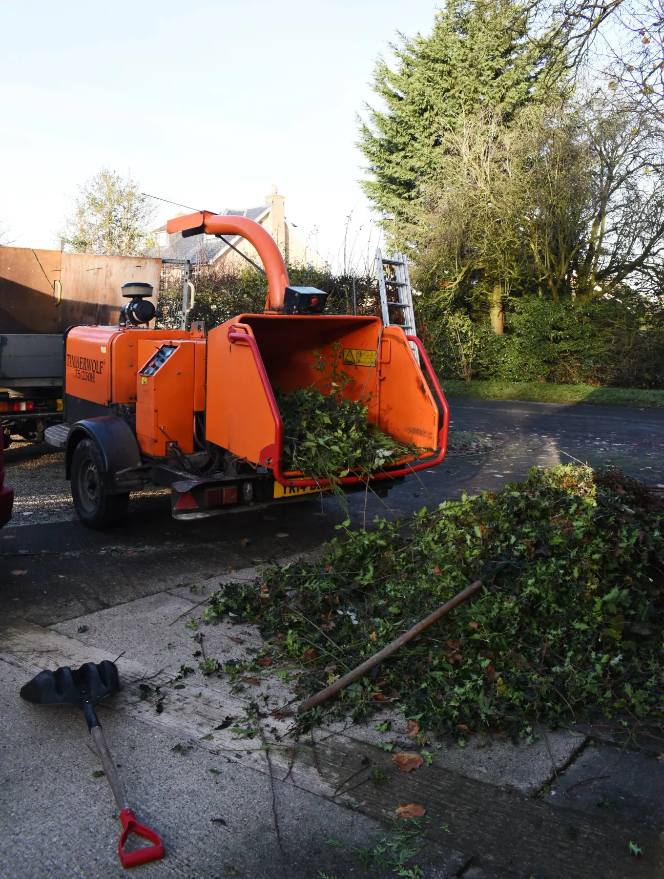 Towable wood chipper set up on a driveway with brash ready to feed